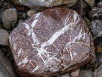 Rötlicher Stein durchzogen von weißen Einlagerungen